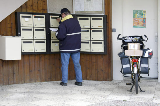 郵便受けに郵便を入れる男性