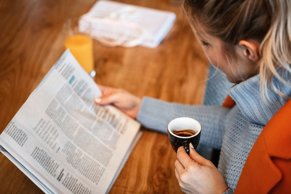 コーヒーを片手に新聞を読む女性